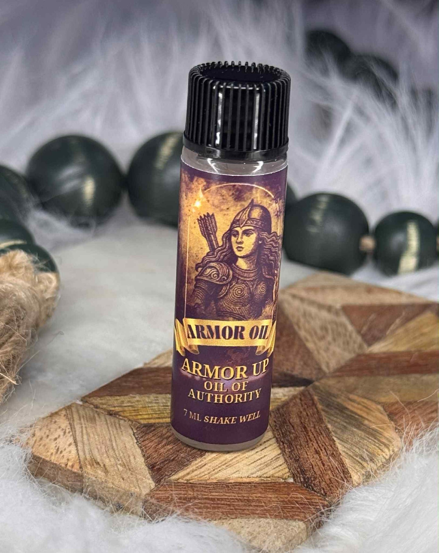 7 ml bottle of Armor Oil 'Armor Up Oil of Authority' on a wooden surface with dark green beads in the background.